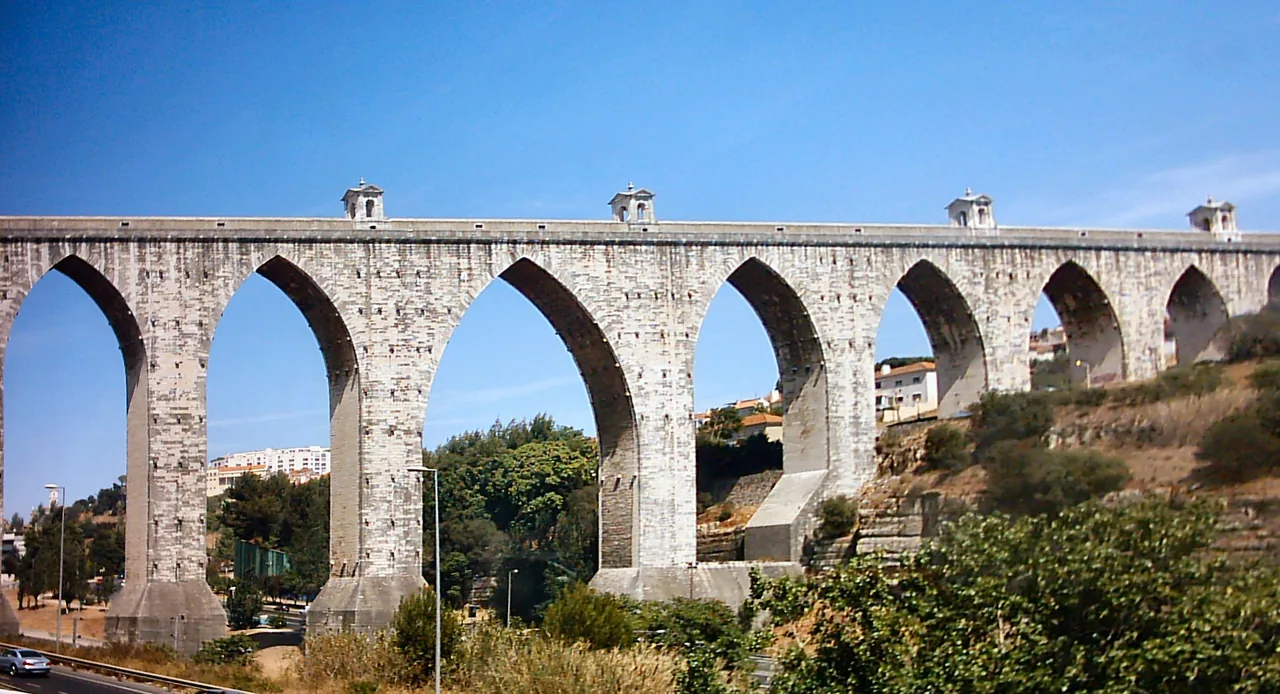 Stone arches of the Águas Livres Aqueduct beneath a clear blue sky