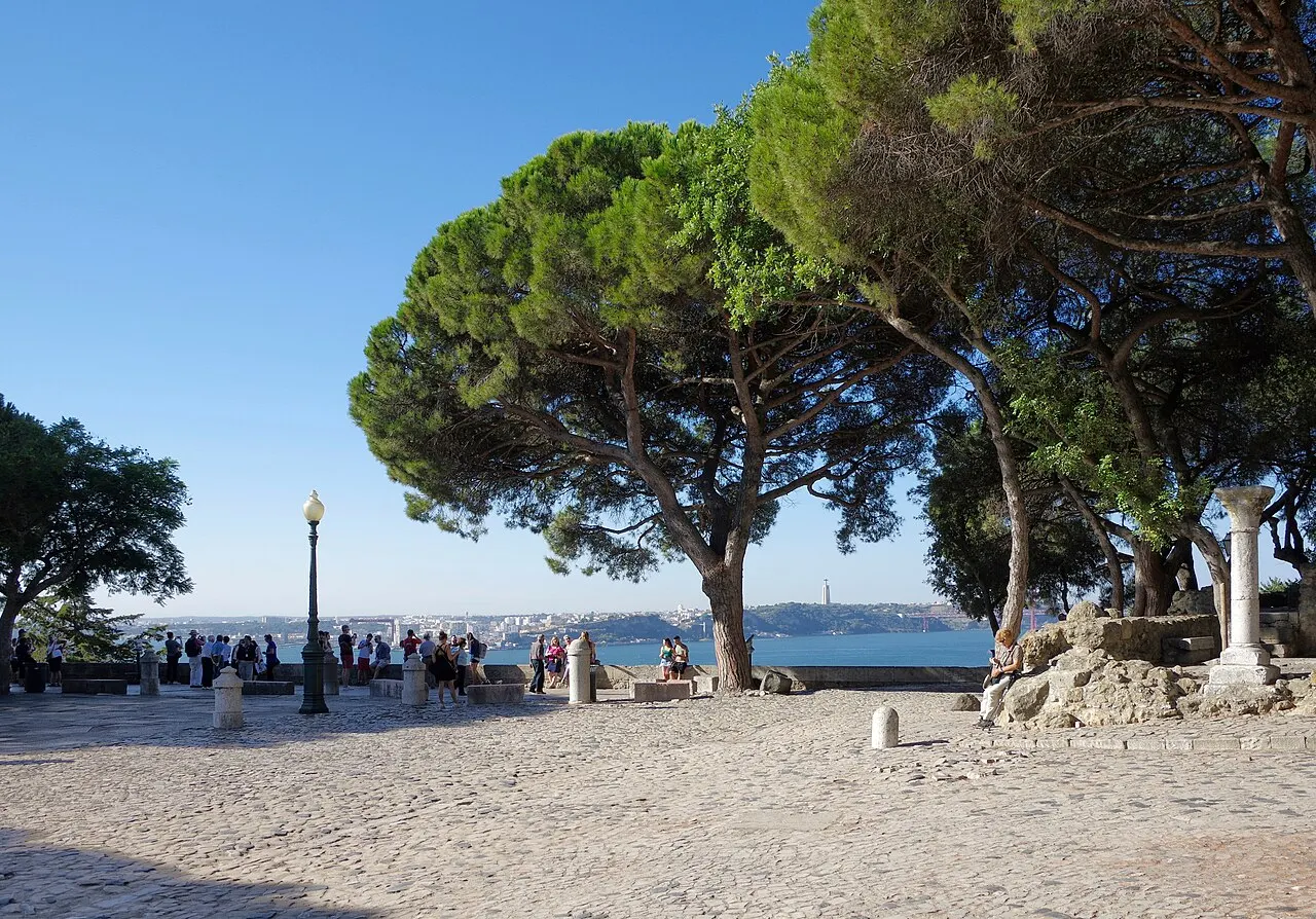 Trees and visitors on the castle viewpoint terrace overlooking the Tagus.