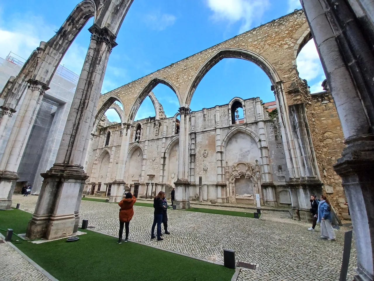 Visitors walking between the stone columns and open arches at Carmo.
