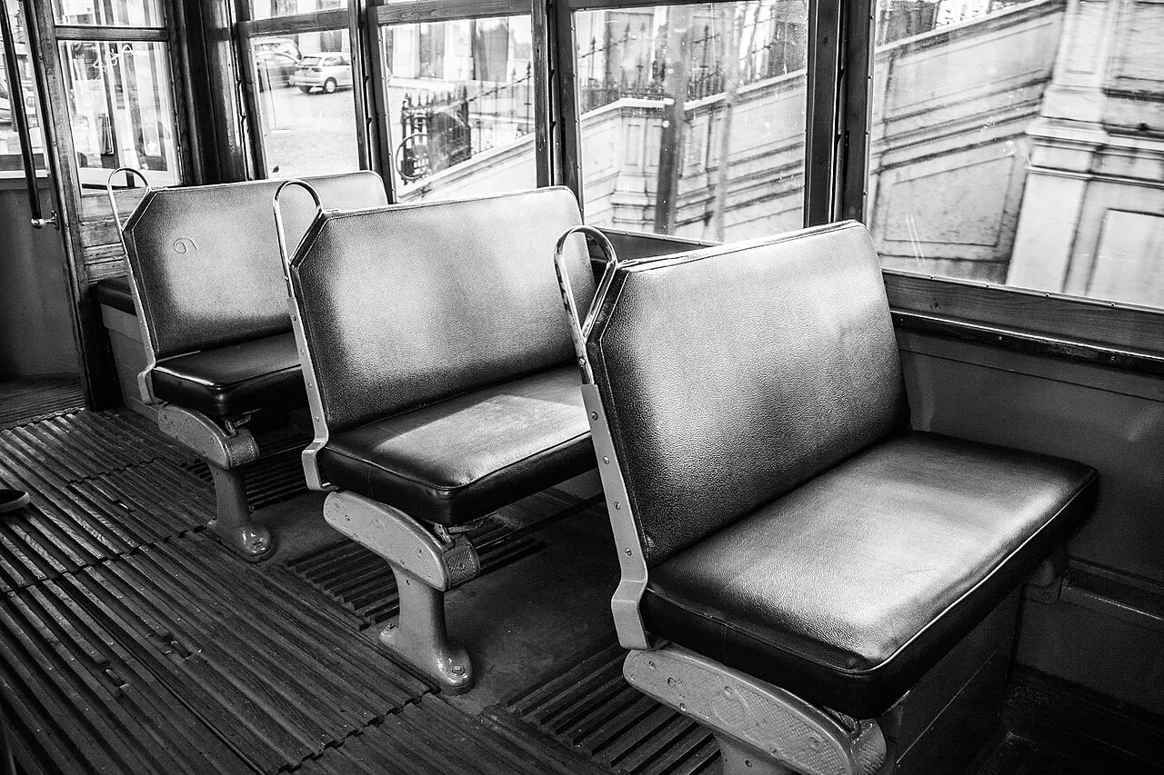 Black-and-white view of Tram 28’s upholstered benches, wooden floor and large windows overlooking Lisbon’s streets.