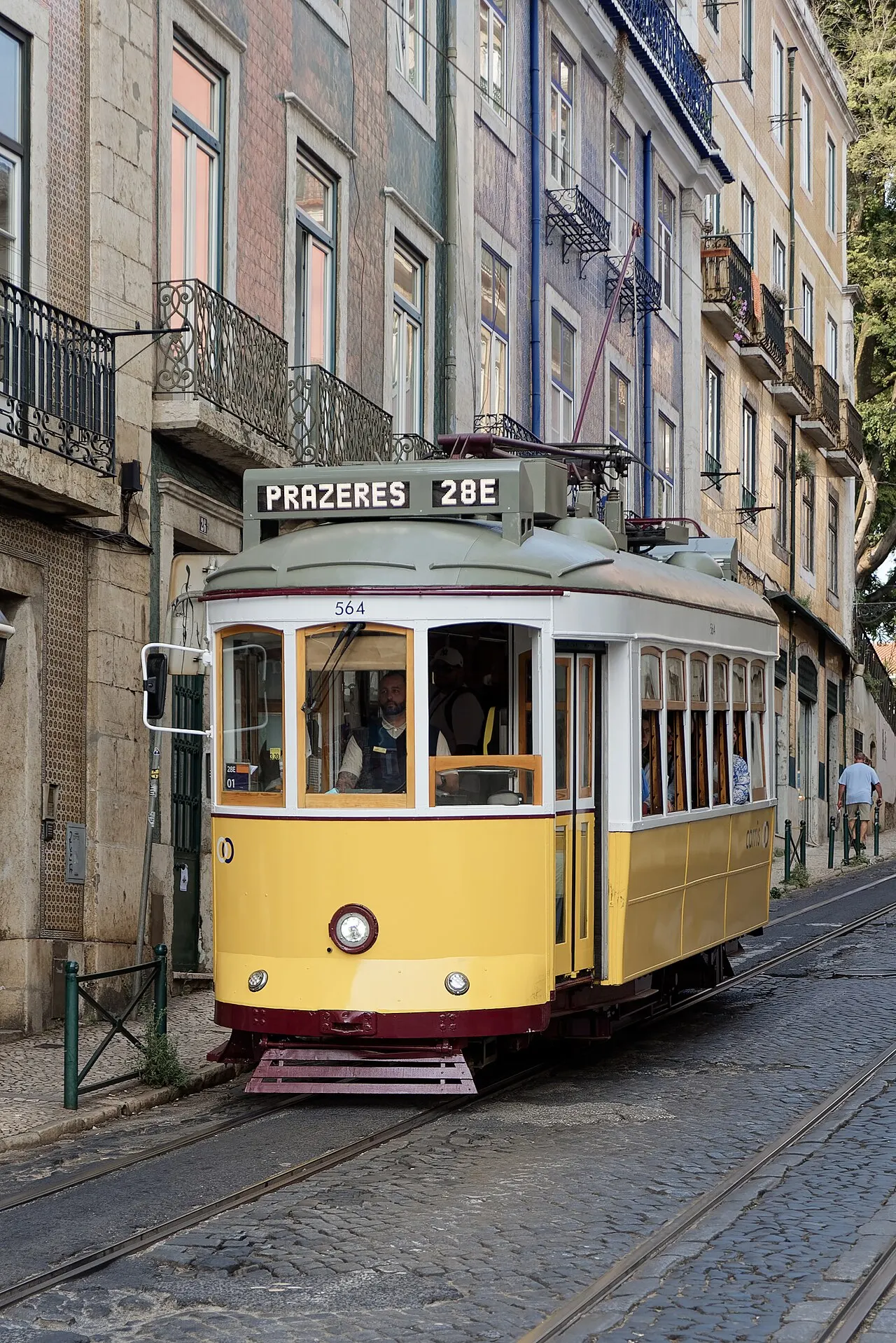 A yellow Tram 28E marked Prazeres between tiled buildings on Rua Augusto Rosa.
