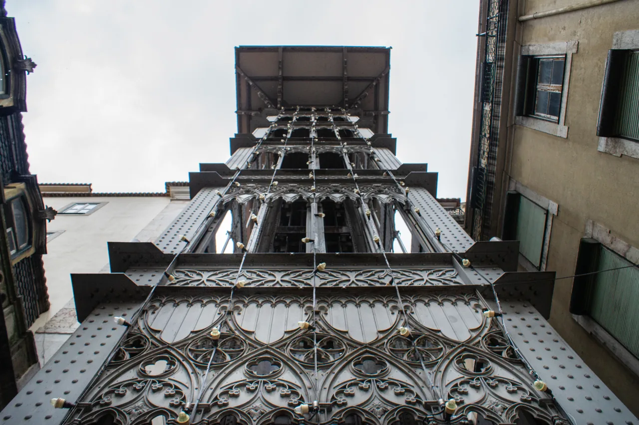 Decorative iron arches and the tall framework of Santa Justa Lift, seen from street level.