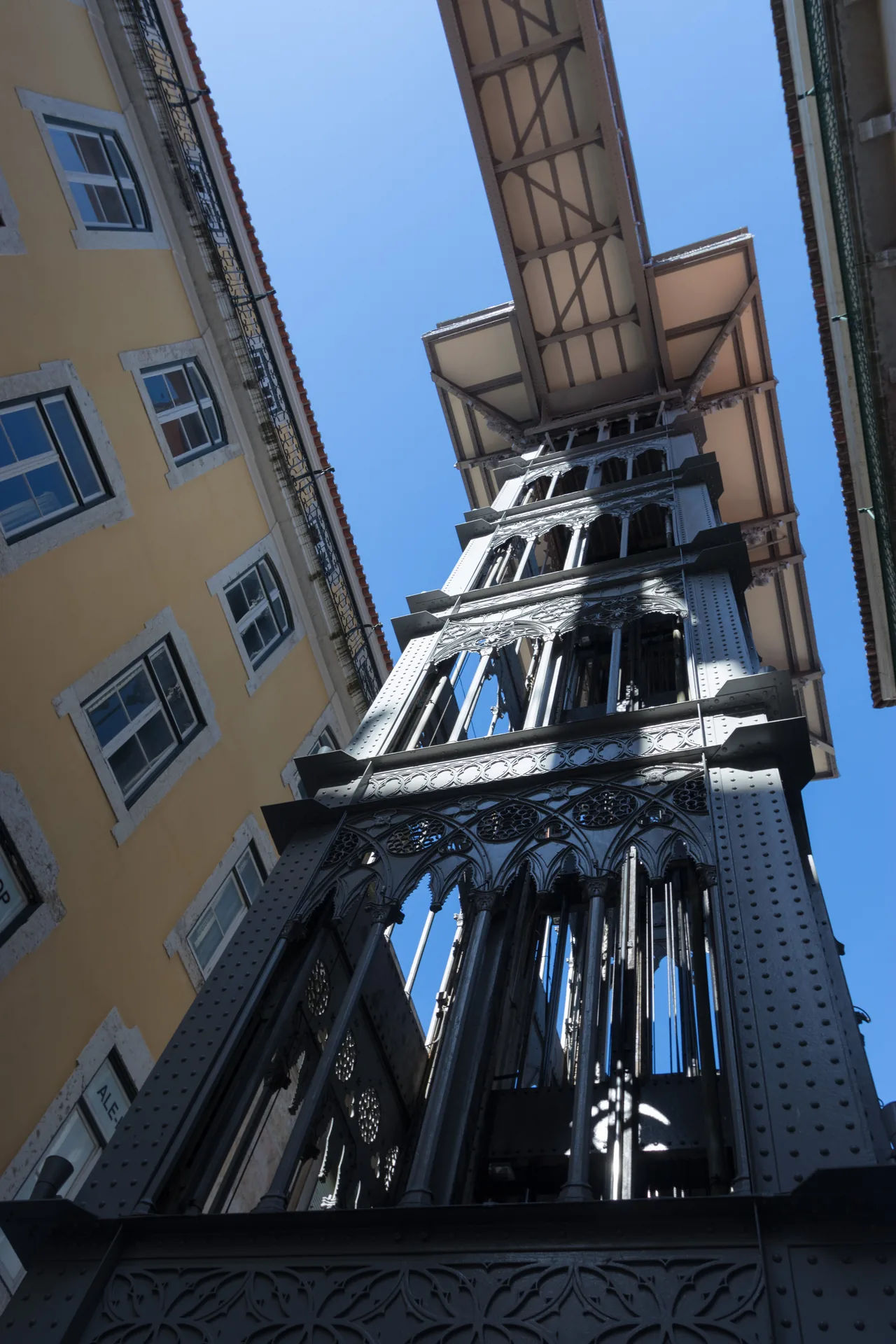 Santa Justa Lift rising between buildings, with its upper bridge overhead.