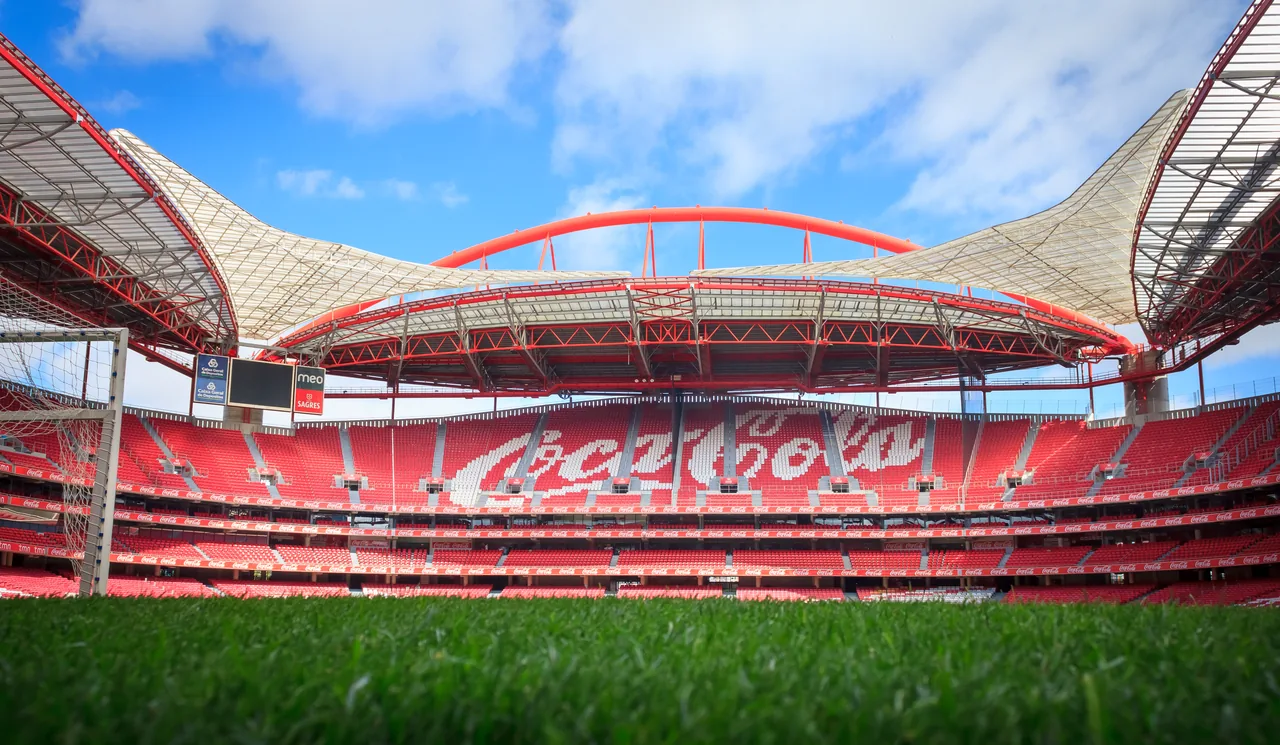 The pitch and red seating beneath the roof of Benfica’s Estádio da Luz.