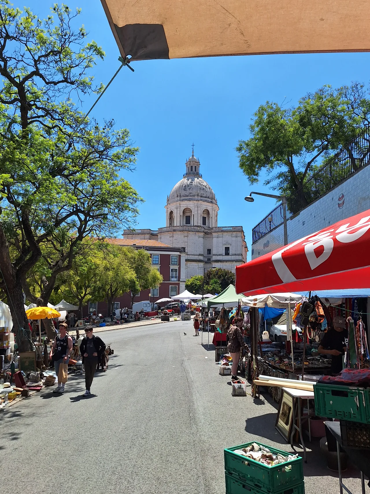 Bancas e visitantes da Feira da Ladra com o Panteão Nacional ao fundo.