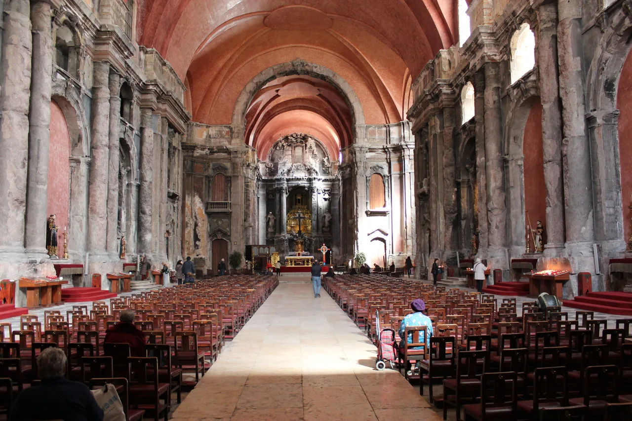 Fire-scarred stone columns beneath the warm red vault of São Domingos Church