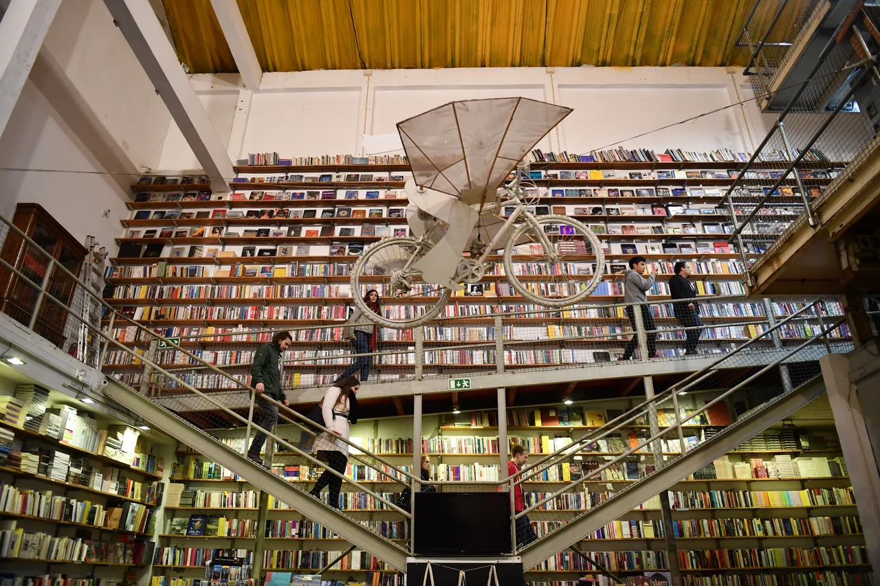 Tall bookshelves and a suspended bicycle inside Ler Devagar bookshop.