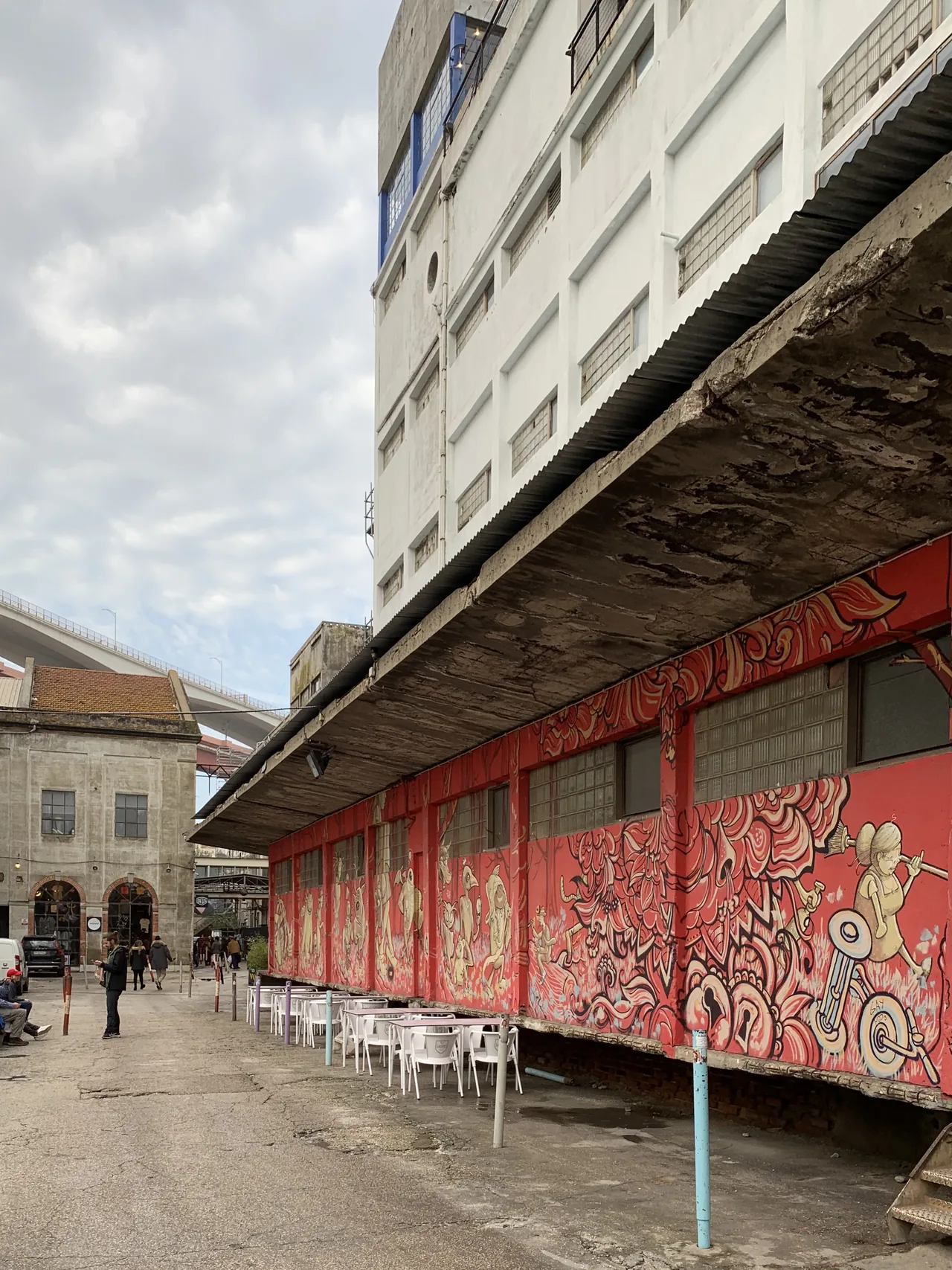 A covered industrial passage with metal beams and red-painted shutters at LX Factory.