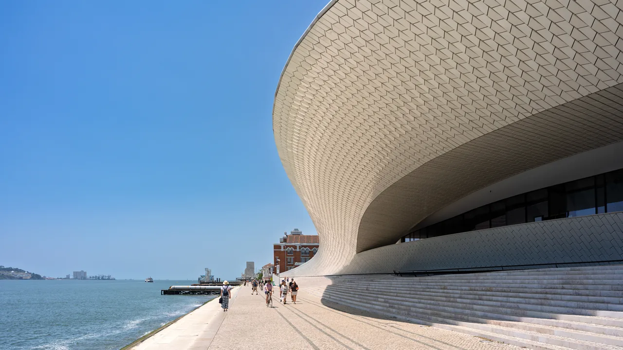 MAAT’s curved white-tiled façade above the riverside walkway beside the Tagus.