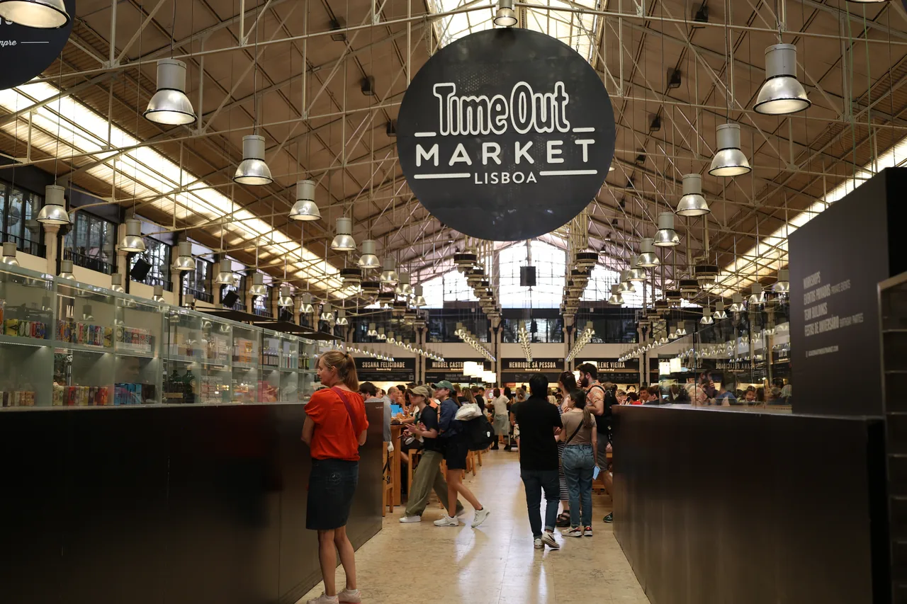 Stalls and diners beneath the high iron roof of Time Out Market in Lisbon.