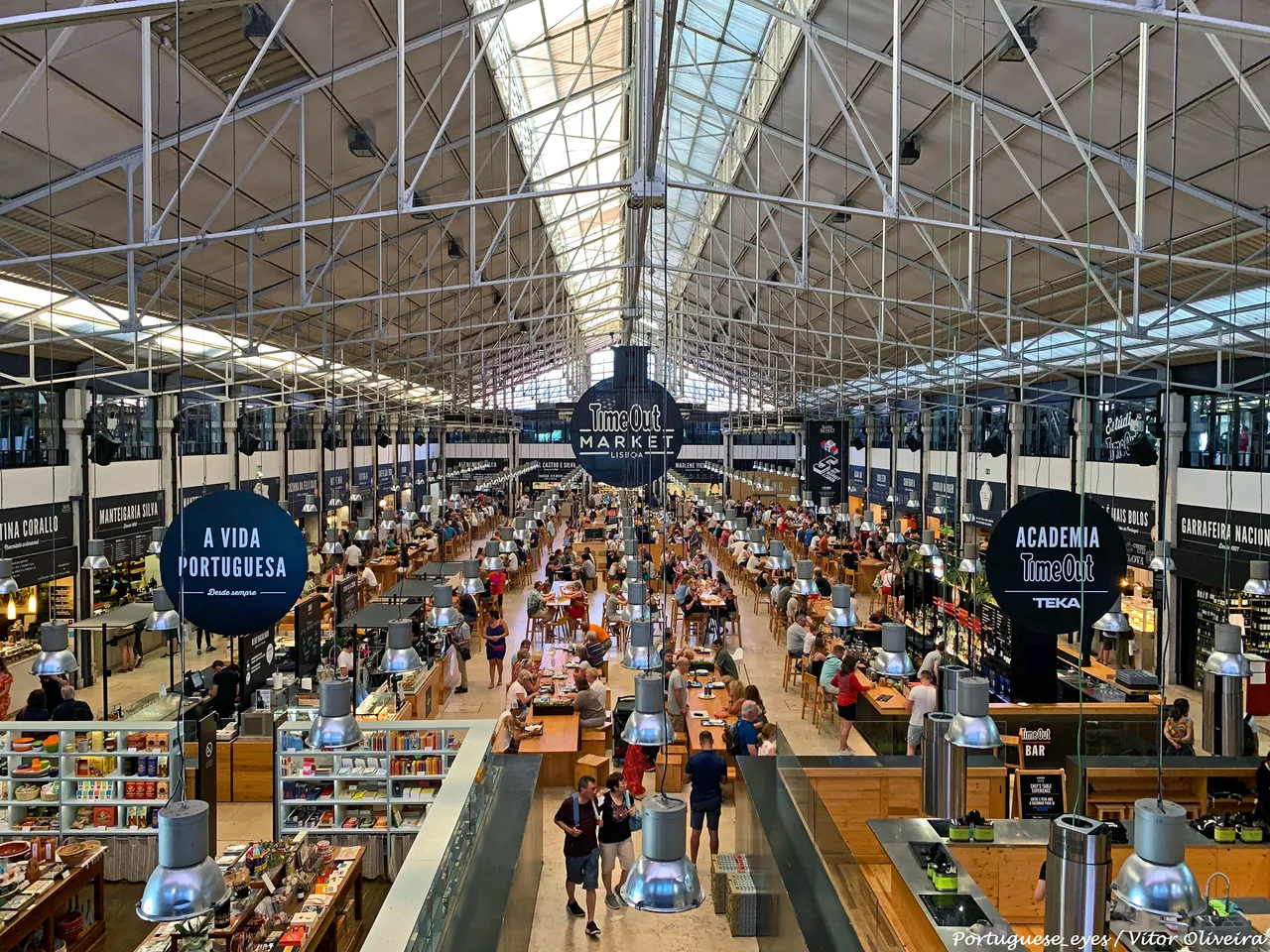 Longas mesas partilhadas rodeadas por balcões de comida no Time Out Market.