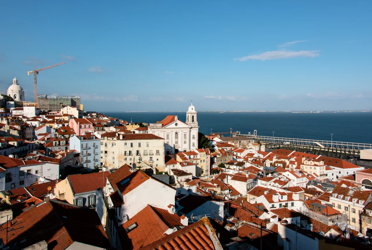 Red roofs and church towers in Alfama with the Tagus beyond, seen from Santa Luzia.