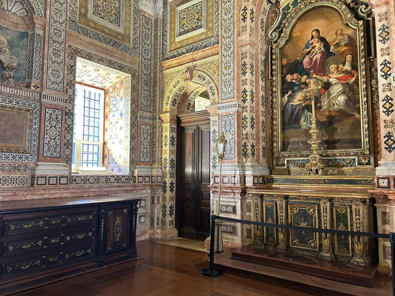 Patterned marble walls and religious paintings in São Vicente de Fora’s sacristy.