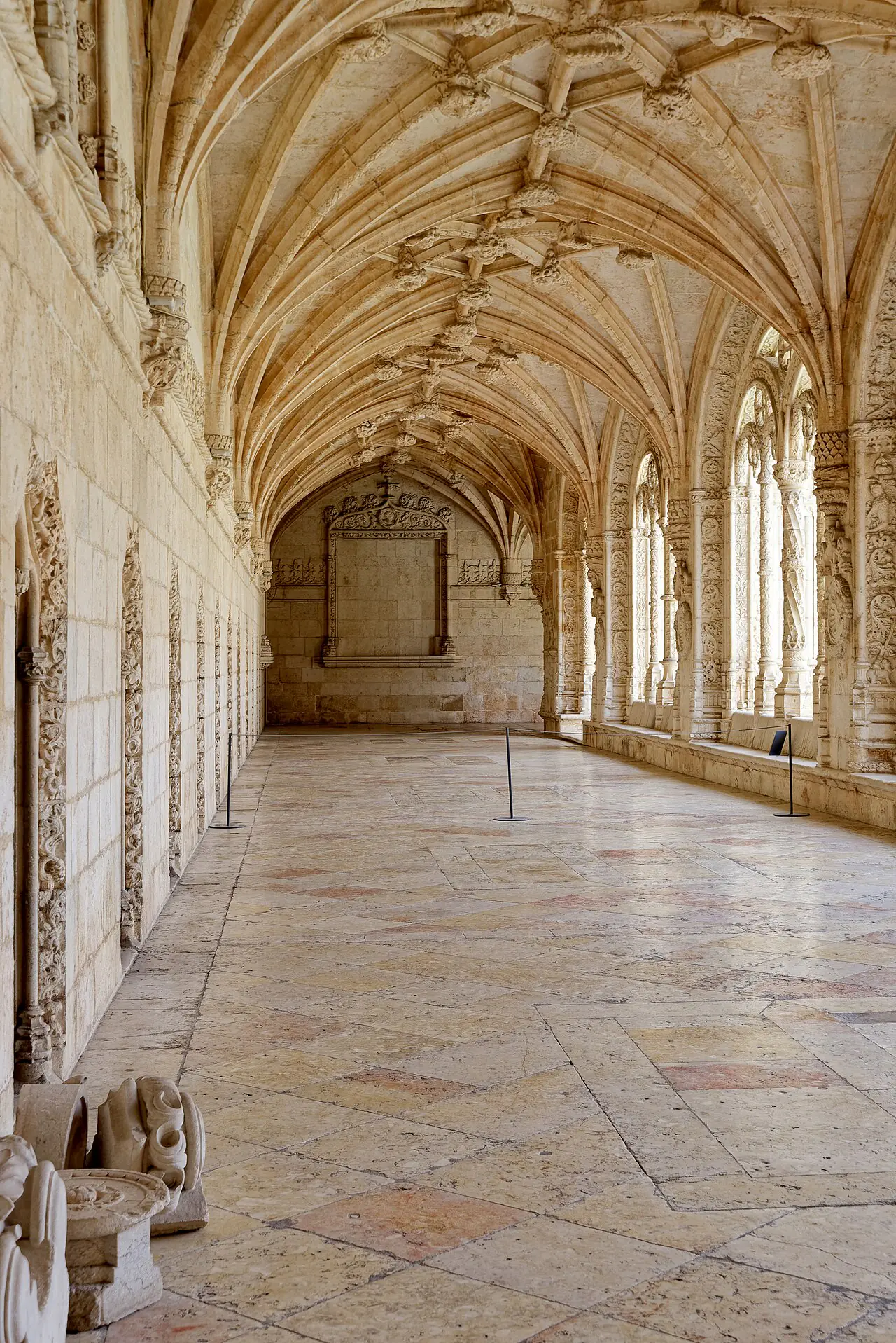 Ribbed stone vaults above a long cloister gallery at Jerónimos Monastery, with carved arches opening onto the courtyard.