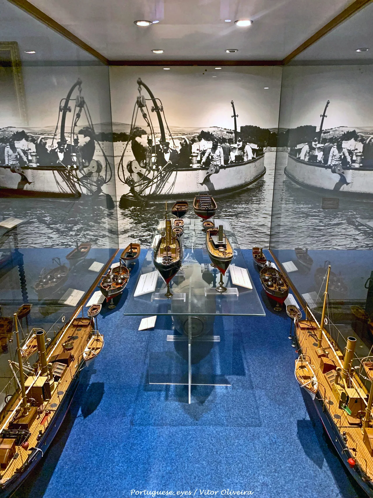 Maquetas de embarcaciones de casco alargado, con aparejos detallados, en una vitrina azul del Museo de Marina.