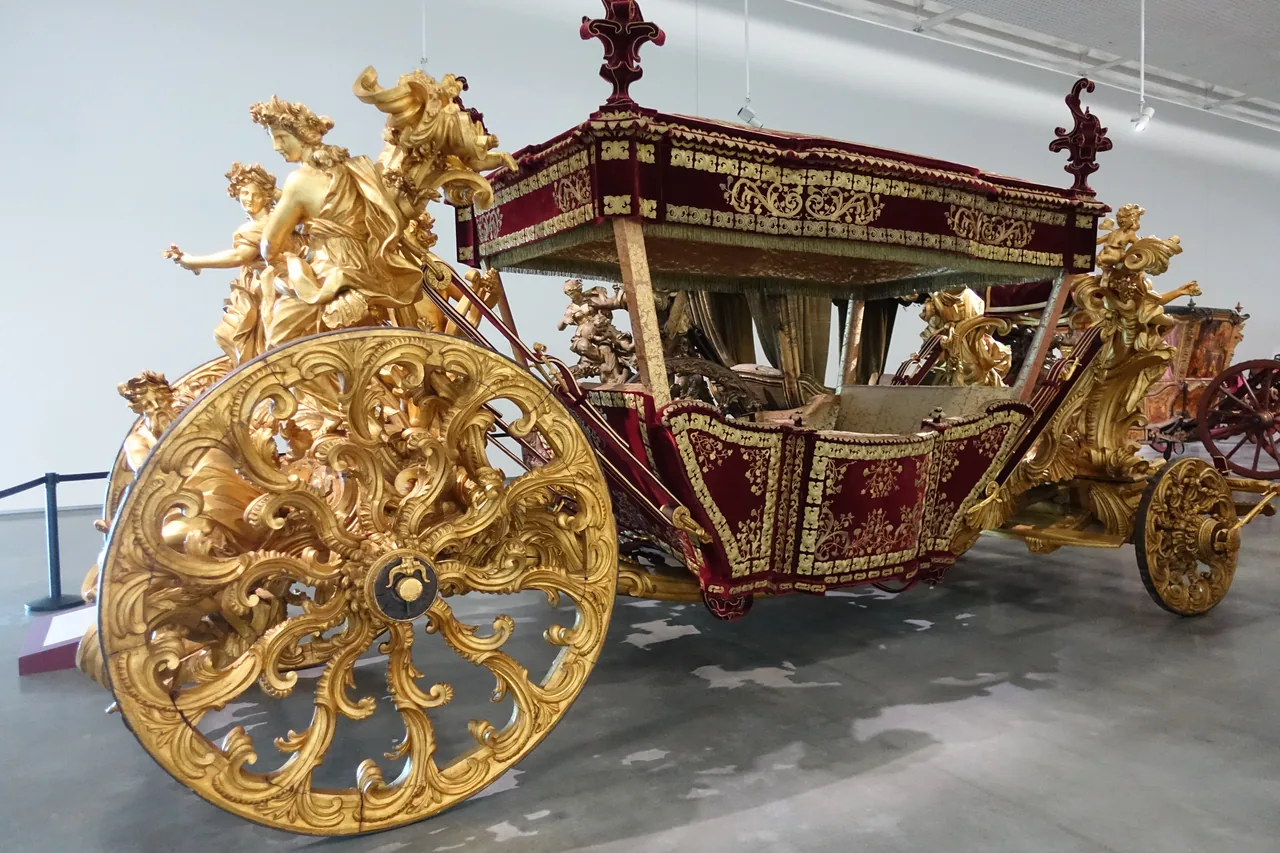 The gilded Coach of the Oceans with sculpted figures and ornate wheels in the National Coach Museum.