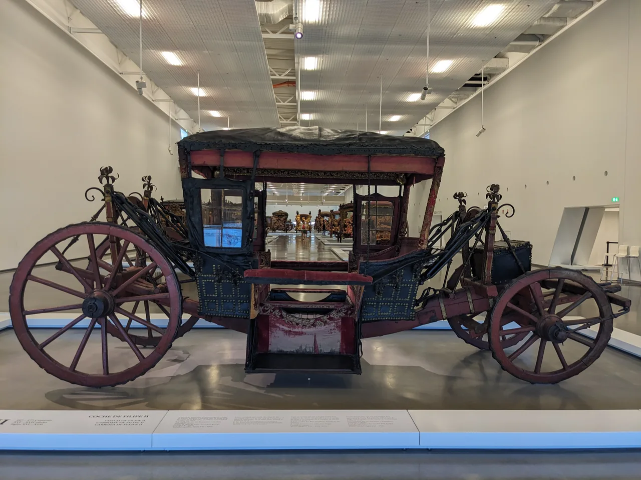 Coche escuro em forma de caixa associado a D. Filipe II de Portugal, exposto com as suas grandes rodas de madeira.