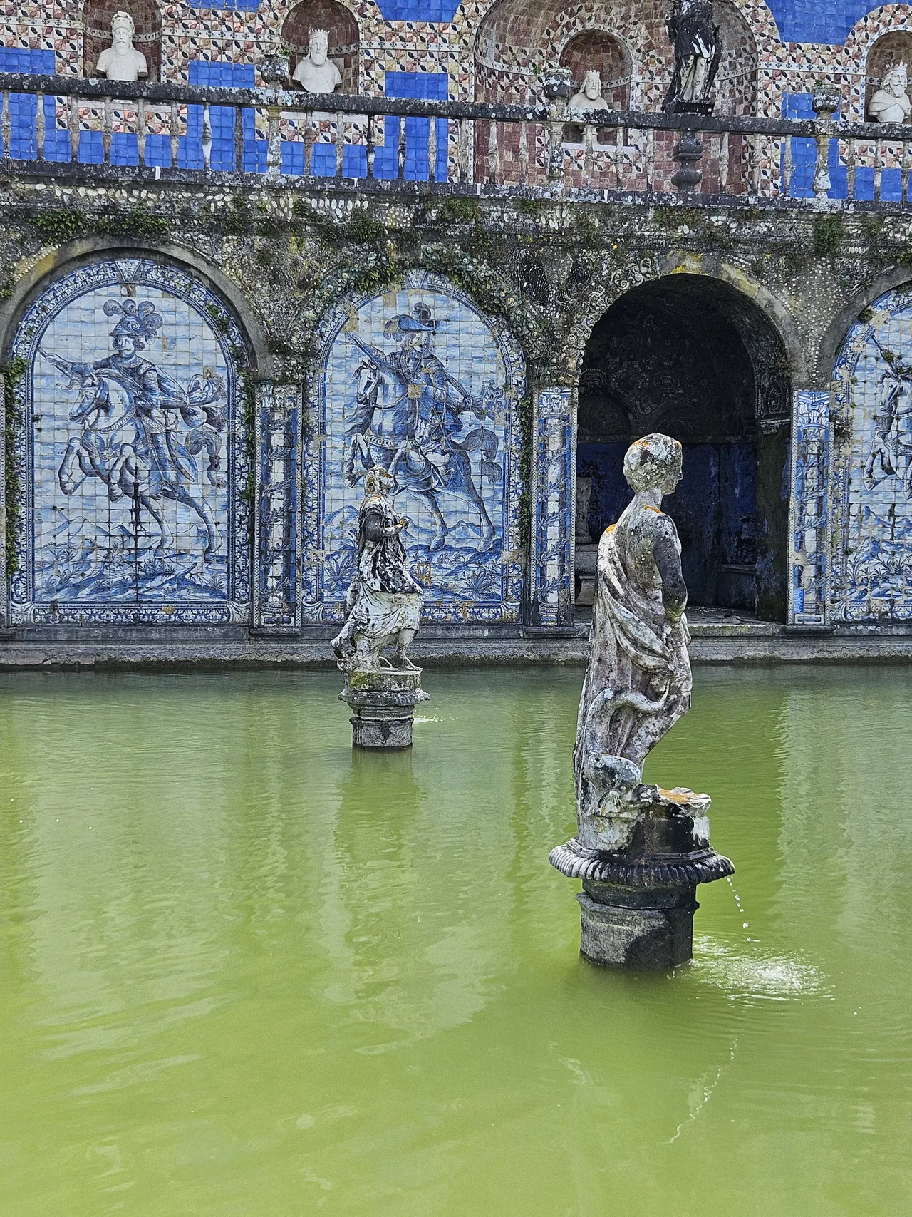 Escultura en el estanque frente a paneles de azulejos azules y blancos del Palacio de Fronteira