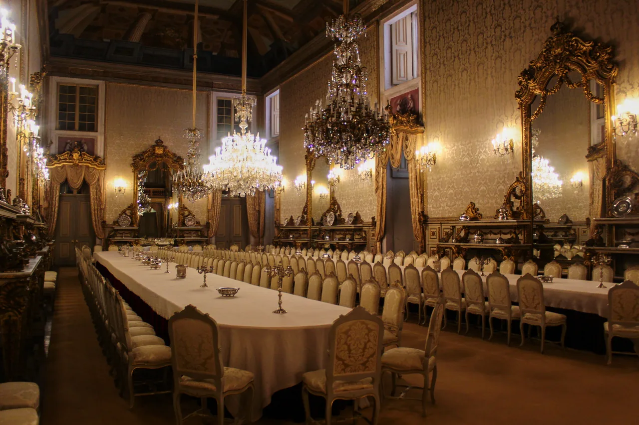 A long formally laid dining table beneath chandeliers at Ajuda Palace.
