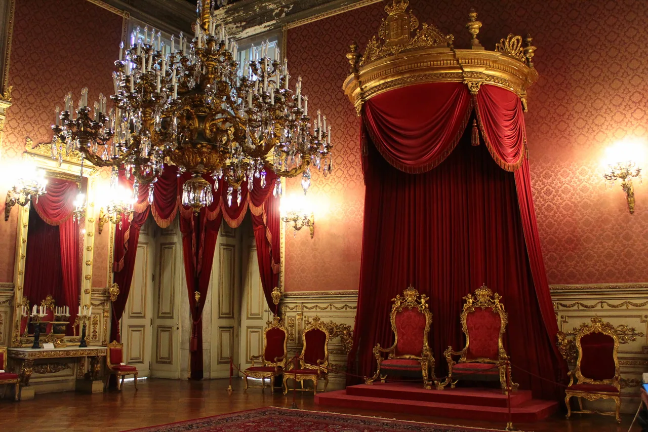 Red drapery, gilded chairs and chandeliers in the throne room at Ajuda Palace.