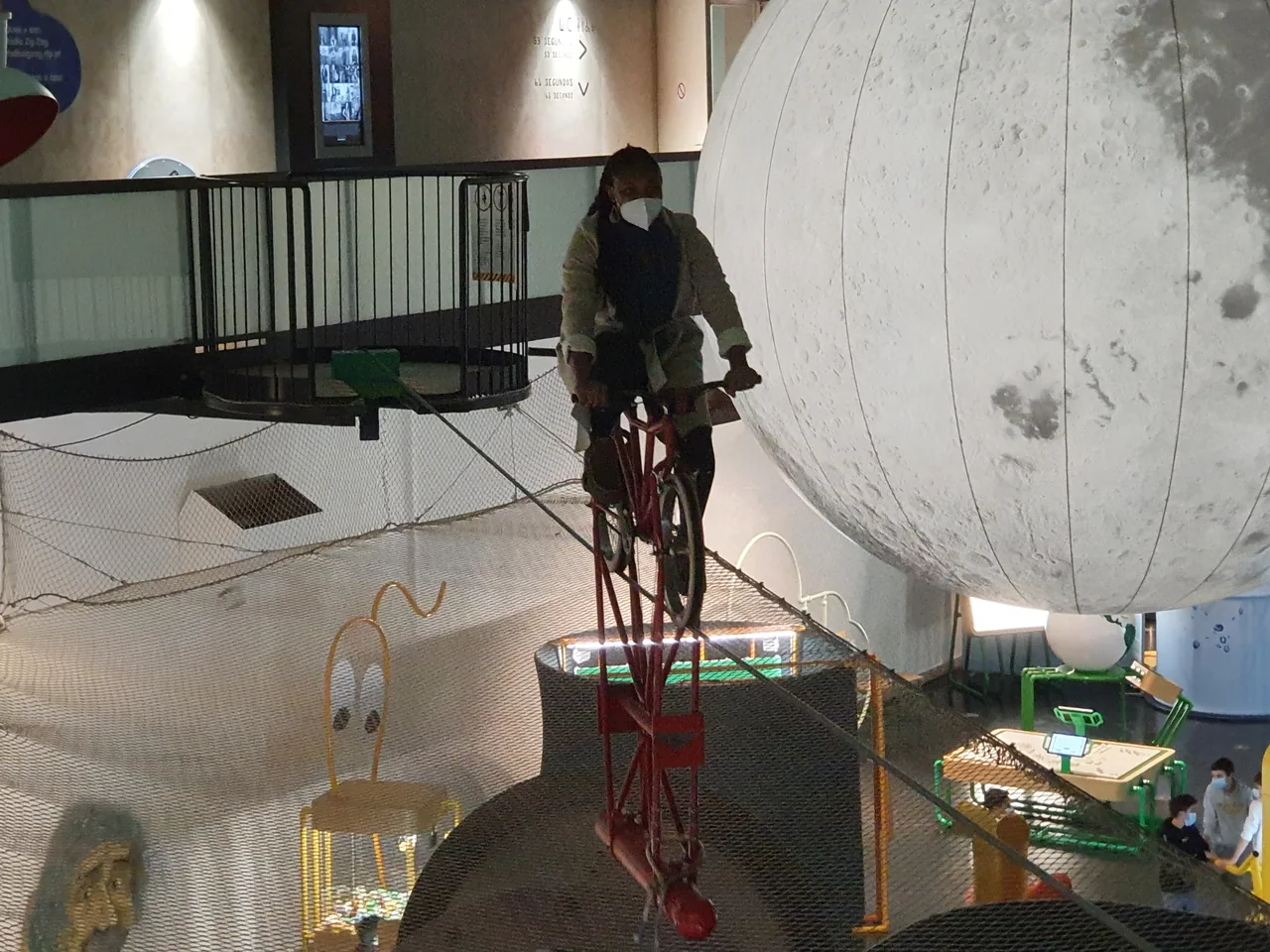A visitor riding the suspended bicycle at Pavilhão do Conhecimento