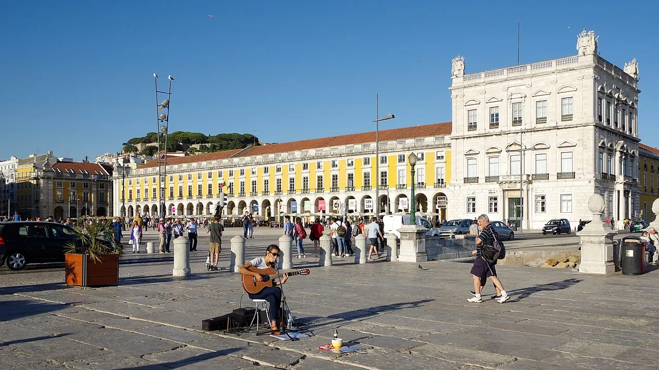 People on the waterfront promenade in front of Praça do Comércio’s yellow arcades.