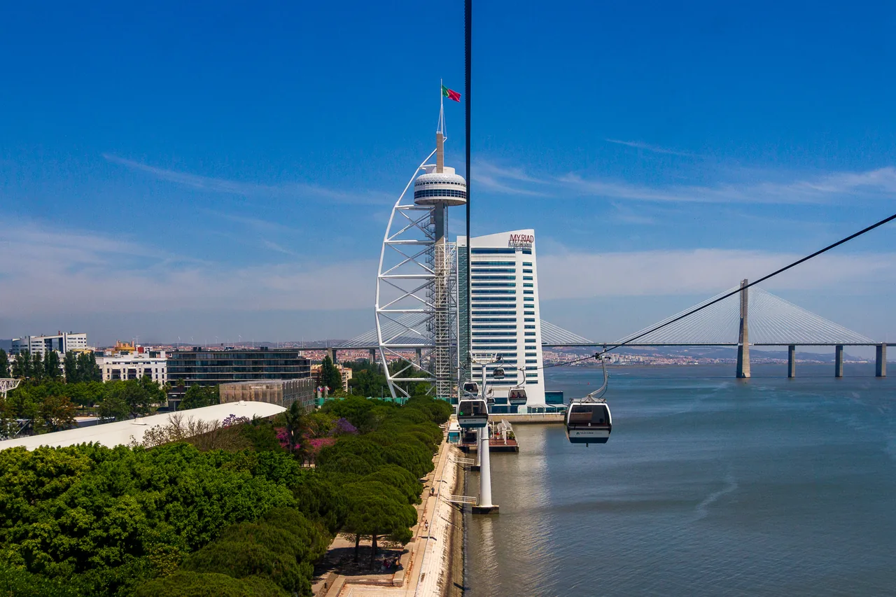 Cable-car cabins travelling beside the Tagus towards the Vasco da Gama Tower.