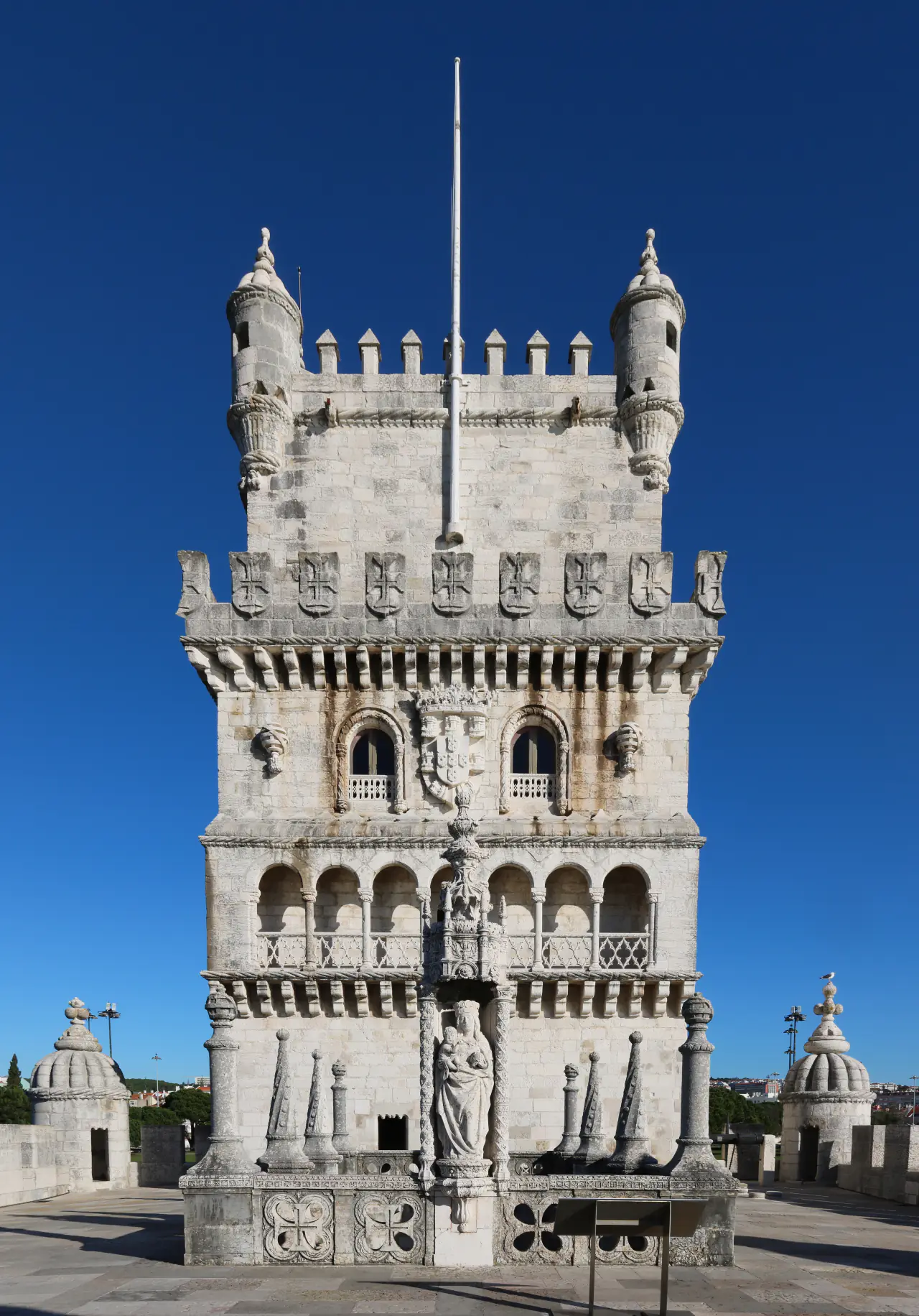Belém Tower’s carved balconies, arcaded windows and corner turrets beneath a clear blue sky.