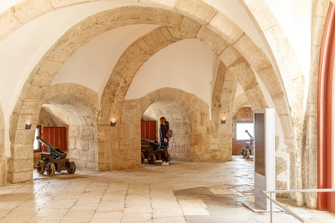 Vaulted stone interior of Belém Tower’s bastion, with cannon displays beside the openings.
