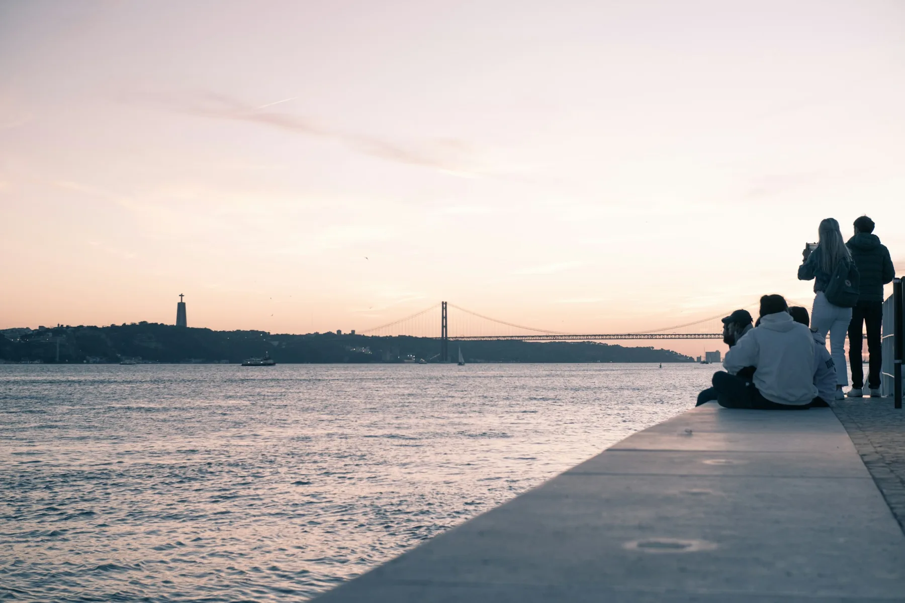 People watching the sun set beside the Tagus in Lisbon.