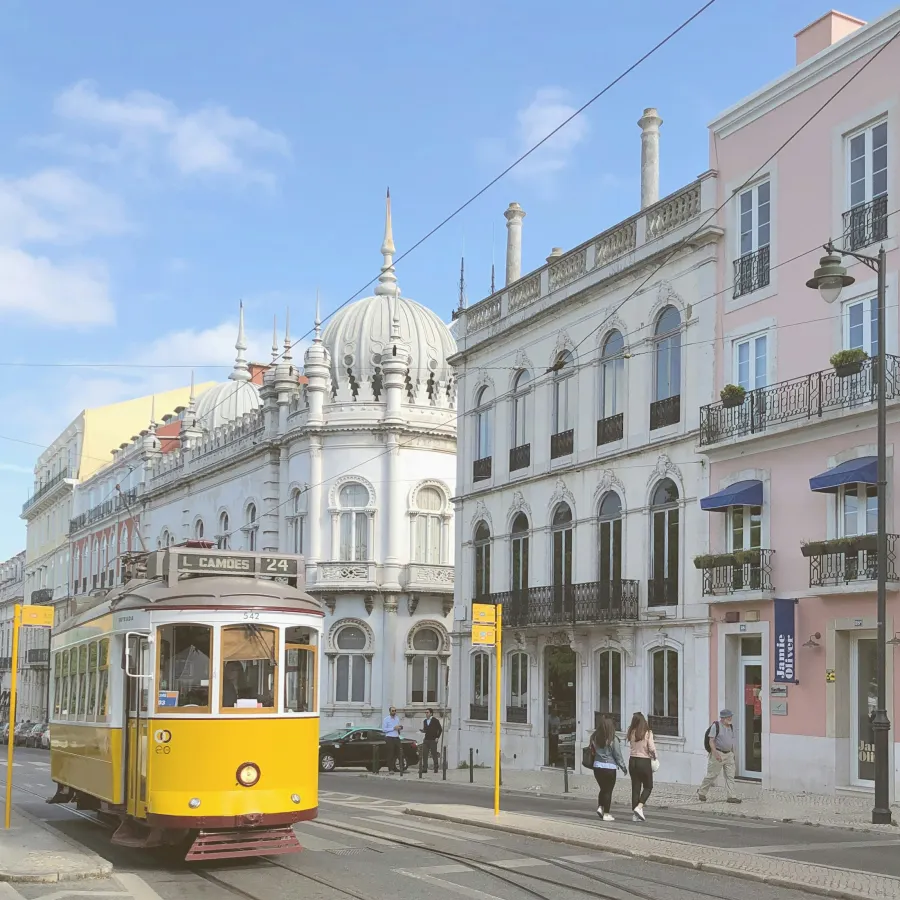 A yellow tram beside historic buildings near Príncipe Real